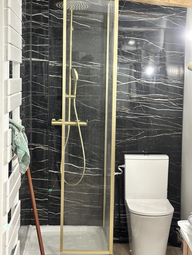 Salle d'eau après rénovation par CDRA : faïence marbre noir et robinetterie dorée