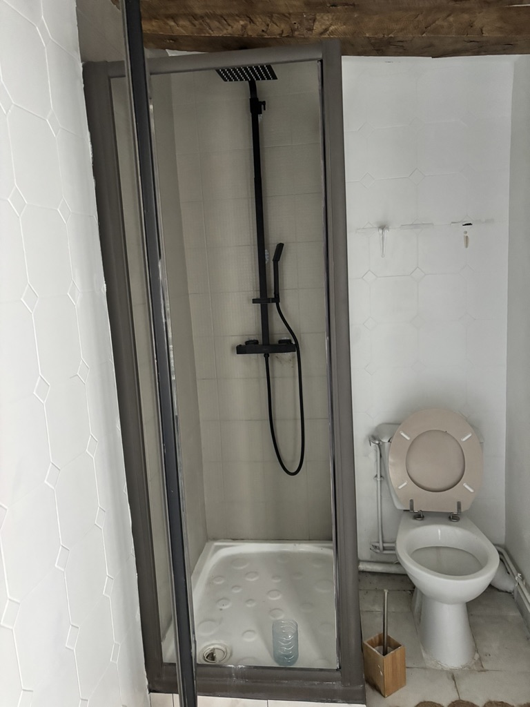 Salle d'eau avant rénovation : carrelage blanc daté et sanitaires vieillissants